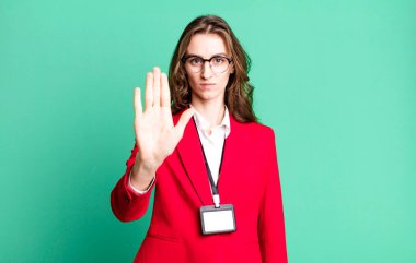 Genç ve güzel bir kadın ciddi görünüyor. Avuç içini gösteriyor. Durdurma hareketi yapıyor. VIP geçiş akreditasyon kavramı