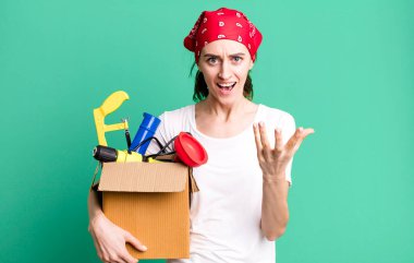 Genç ve güzel bir kadın sinirli, sinirli ve sinirli görünüyor. kahya ve alet çantası kavramı