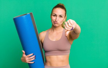 Genç ve güzel bir kadın kendini kötü hissediyor, baş parmağını kaldırıyor. fitness ve yoga konsepti