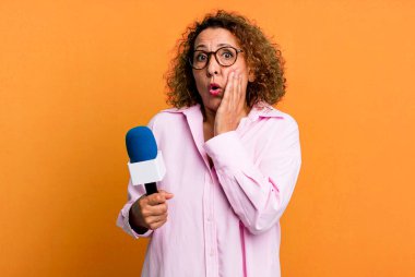 pretty middle age woman feeling shocked and scared. tv presenter with a microphone concept