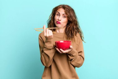 hispanic pretty young woman eating a japanese noodles bowl.