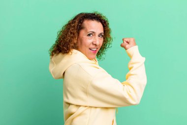 Orta yaşlı İspanyol kadın kendini mutlu, tatmin olmuş ve güçlü hissediyor, kaslı ve formda, spor salonundan sonra güçlü görünüyor.