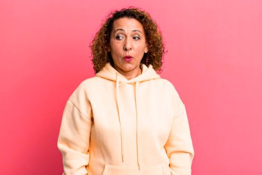 Orta yaşlı İspanyol kadın şok olmuş, mutlu, şaşkın ve şaşırmış hissediyor, ağzı açık bir şekilde yana bakıyor.