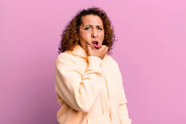 Orta yaşlı, ağzı ve gözleri açık ve eli çenesinde olan İspanyol bir kadın. Hoş olmayan bir şok geçiriyor.