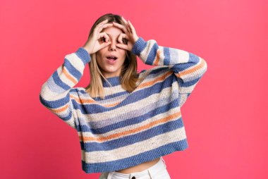 Sarışın, güzel bir kadın şaşkın, şaşkın ve şaşırmış, elinde şaşkın, inançsız bir bakışla gözlük tutuyor.