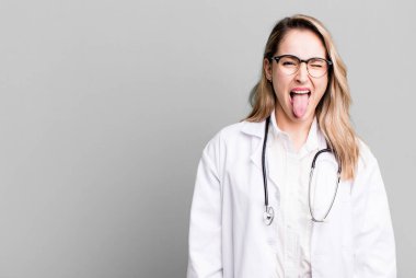 Neşeli ve asi bir tavırla, şakalar yaparak ve dil çıkararak. Tıp öğrencisi ya da doktor.