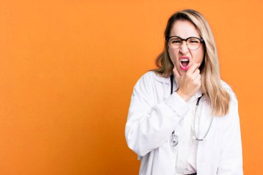 Ağzı ve gözleri açık ve elleri çenesinde. Tıp öğrencisi ya da doktor.