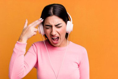 Mutsuz ve stresli görünüyor, intihar jesti silah işareti yapıyor. kulaklıkla müzik dinlemek