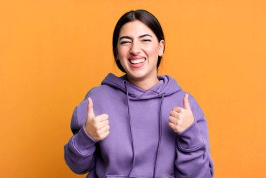 Gülümseyen mutlu, pozitif, kendinden emin ve başarılı, iki başparmağı da havada.