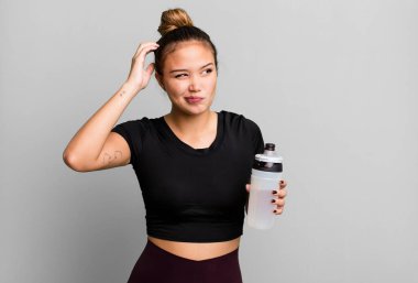 hispanic pretty woman smiling happily and daydreaming or doubting. gym and fitness concept