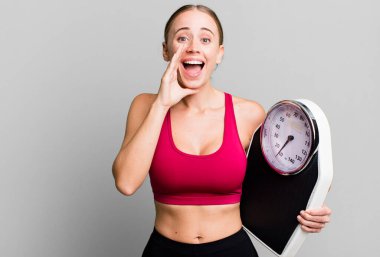 caucasian pretty woman feeling happy,giving a big shout out with hands next to mouth. fitness and diet concept