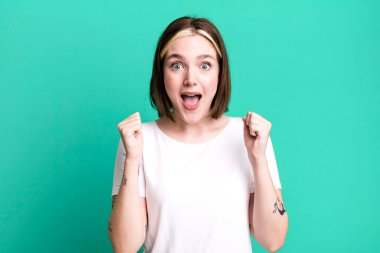 Genç ve güzel bir kadın şokta, gülüyor ve başarıyı kutluyor.