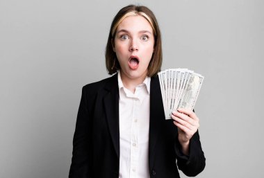 young pretty woman looking very shocked or surprised. dollar banknotes