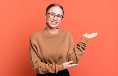 Gururla ve özgüvenle gülümseyen, mutlu ve tatmin olmuş hisseden ve fotokopi alanında bir konsept gösteren