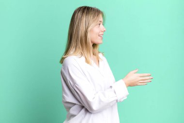 Sarışın, güzel bir kadın gülümsüyor, seni selamlıyor ve başarılı bir anlaşma için el sıkışmayı teklif ediyor, işbirliği konsepti.