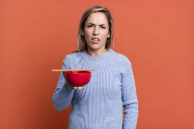 pretty blonde woman feeling puzzled and confused. japanese noodles concept