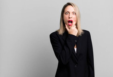pretty blonde woman with mouth and eyes wide open and hand on chin. businesswoman concept