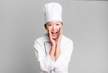 pretty asian woman feeling happy,giving a big shout out with hands next to mouth. restaurant chef concept