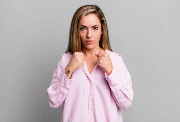 blonde adult woman looking confident, angry, strong and aggressive, with fists ready to fight in boxing position