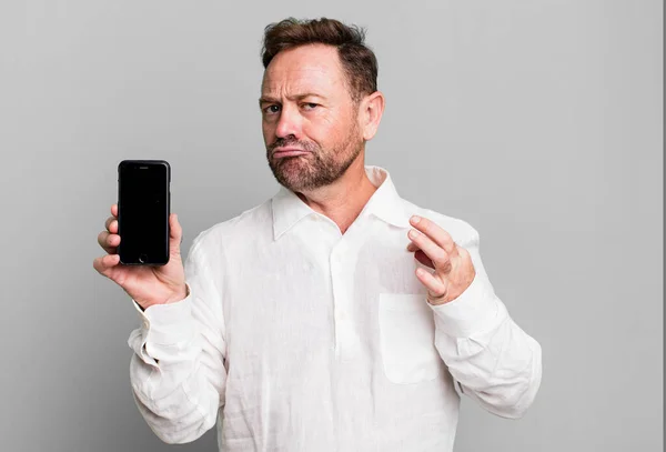 middle age man looking arrogant, successful, positive and proud. showing a smartphone
