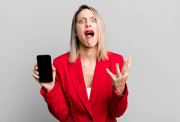 pretty blonde woman looking desperate, frustrated and stressed. businesswoman showing a phone screen