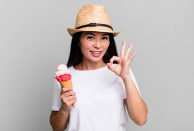 hispanic pretty woman feeling happy, showing approval with okay gesture. ice cream and summer concept