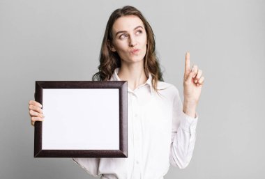 Genç ve güzel bir kadın boş bir çerçeve kopyası tutuyor.