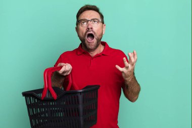 middle age man looking desperate, frustrated and stressed. empty shopping basket concept