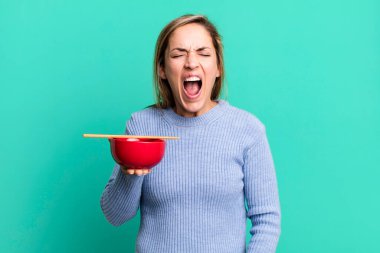 pretty blonde woman shouting aggressively, looking very angry. japanese noodles concept