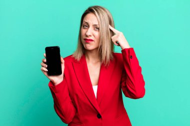 pretty blonde woman feeling confused and puzzled, showing you are insane. businesswoman showing a phone screen