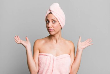 pretty blonde woman feeling puzzled and confused and doubting. bathrobe and beauty concept