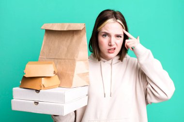 young pretty woman feeling confused and puzzled, showing you are insane. take away fast food concept
