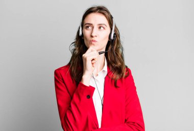 Genç, güzel bir kadın düşünüyor, kuşkulu ve şaşkın hissediyor. tele pazarlamacı kavramı