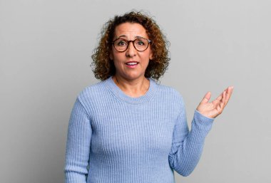 Orta yaşlı İspanyol kadın mutlu, şaşırmış ve neşeli, pozitif bir tavırla gülümseyen, bir çözüm ya da fikir gerçekleştiren