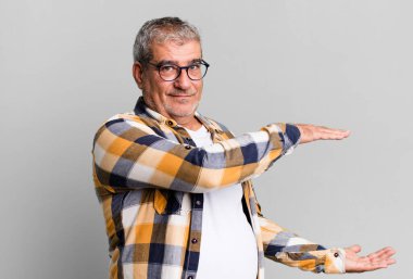 Orta yaşlı, gülümseyen, mutlu, pozitif ve memnun hisseden, fotokopi alanında nesne ya da konsept tutan ya da gösteren biri.