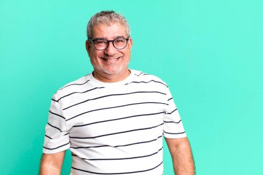 Büyük, dostane, kaygısız bir gülümsemesi olan orta yaşlı bir adam. Olumlu, rahat ve mutlu görünüyor.