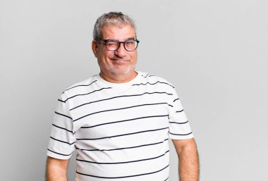 Orta yaşlı bir adam mutlu ve arkadaş canlısı görünüyor, gülümsüyor ve olumlu bir tavırla sana göz kırpıyor.