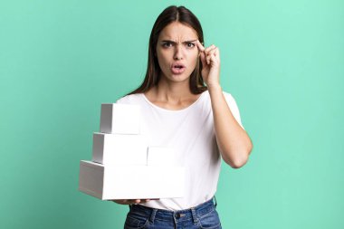 young pretty woman looking surprised, realizing a new thought, idea or concept. blank white boxes