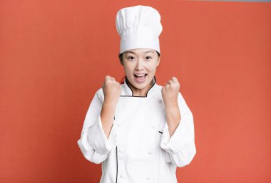 pretty asian woman feeling shocked,laughing and celebrating success. restaurant chef concept