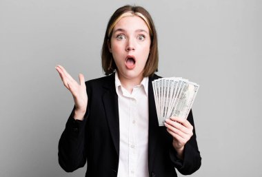 young pretty woman feeling extremely shocked and surprised. dollar banknotes