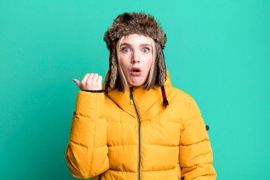 young pretty woman looking astonished in disbelief. cold and coat concept