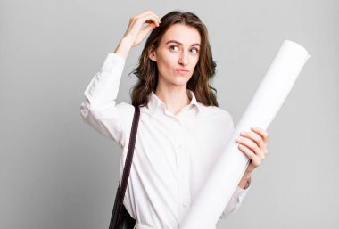 young pretty woman feeling puzzled and confused, scratching head. architect concept