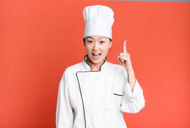 pretty asian woman feeling like a happy and excited genius after realizing an idea. restaurant chef concept