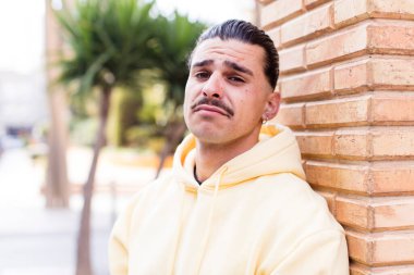 young cool man feeling sad and whiney with an unhappy look, crying with a negative and frustrated attitude