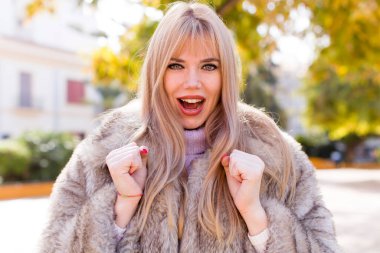 Genç, güzel bir kadın sinirli, sinirli, kızgın bakışlar ve sıkı yumruklar ile agresif bir şekilde bağırıyor.