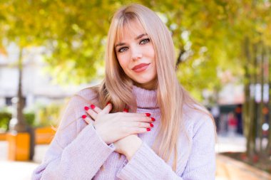 Genç, güzel bir kadın romantik, mutlu ve aşık, neşeyle gülümseyen ve kalbe yakın el ele tutuşan