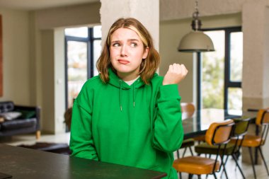 pretty caucasian woman looking confident, angry, strong and aggressive, with fists ready to fight in boxing position. home interior concept