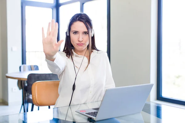 stock image young pretty woman looking serious showing open palm making stop gesture. telemarketer concept