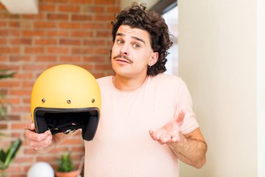 Evin içinde motosiklet kaskı tutan genç ve yakışıklı bir adam.