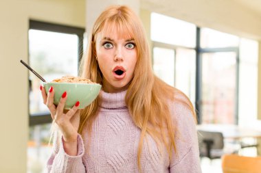 Genç ve güzel bir kadın kahvaltı kasesiyle evin içinde.